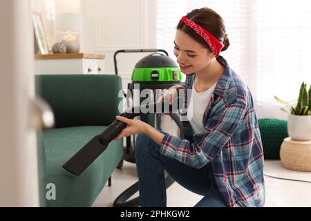 Junge Frau saugt Sofa im Wohnzimmer Stockfoto