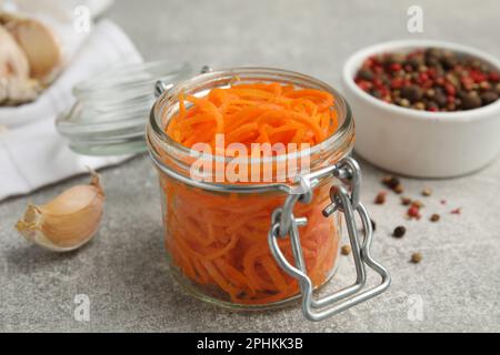 Köstlicher koreanischer Karottensalat im Glasgefäß auf einem grauen Tisch Stockfoto