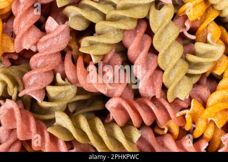 Reisgemüse-Pasta in Spiralform, Draufsicht. Gesunde Reispasta mit Tomaten, Selenera, Karotten und Rüben Stockfoto