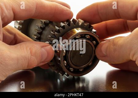 Hände bei der Arbeit mit Getriebeteilen, Hände im Einsatz mit Getriebeteilen Stockfoto