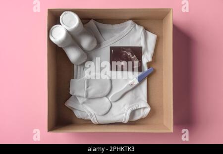 Box mit Babyzeug und Schwangerschaftstest. Stockfoto