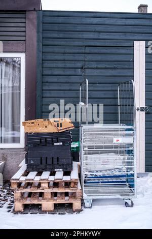 Sandnes, Norwegen, März 12 2023, Transportcontainer und Metallwagen warten auf Abholung vor Einem Laden oder Geschäft an Einem kalten Wintertag in do Stockfoto