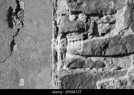 Die Konsistenz alter Steinwände mit kollabiertem Putz. Hintergrund einer schäbigen Gebäudefläche. Zerstörte Wand mit heruntergefallenem Gips. Verwitterte Oberfläche. Kopieren en Stockfoto