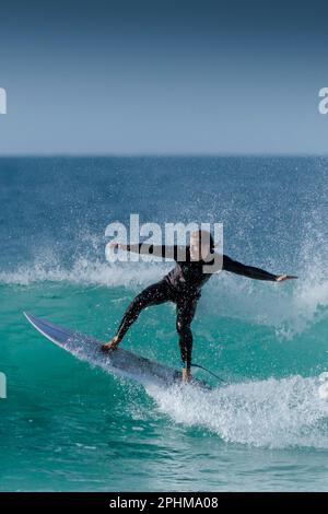 Spektakuläre Surfaktion als männlicher Surfer reitet auf einer Welle im Fistral in Newquay in Cornwall in England in Großbritannien. Stockfoto