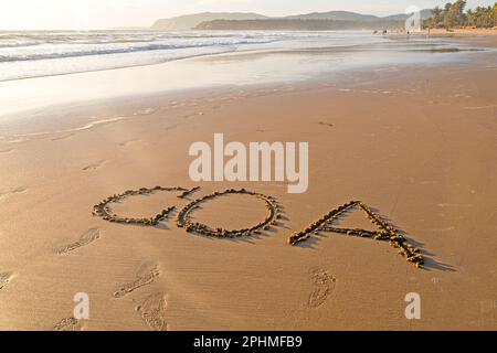 GOA Word auf sandiger Oberfläche, Sommerstrand mit Ozeanküste Stockfoto