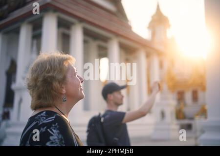 Porträt von Senirin und erwachsenem Mann, während Sie die Architektur des buddhistischen Tempels in Bangkok bewundern. Reisende in Thailand. Stockfoto