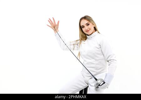 Teenager-Mädchen im Fechtkostüm mit Schwert in der Hand isoliert auf weißem Hintergrund. Fechtermädchen berührt die Spitze des Schwertes mit ihrer Hand. Stockfoto