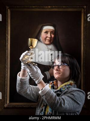 Der Special Collections Manager Dr. Hannah Thomas hält im Rahmen einer Osterausstellung im Bar Convent in York, dem ältesten lebenden Kloster Großbritanniens, den 1630er wiederkehrenden Kelch mit Darstellungen der Stationen des Kreuzes. Bilddatum: Mittwoch, 29. März 2023. Stockfoto