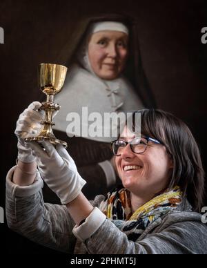 Der Special Collections Manager Dr. Hannah Thomas hält im Rahmen einer Osterausstellung im Bar Convent in York, dem ältesten lebenden Kloster Großbritanniens, den 1630er wiederkehrenden Kelch mit Darstellungen der Stationen des Kreuzes. Bilddatum: Mittwoch, 29. März 2023. Stockfoto