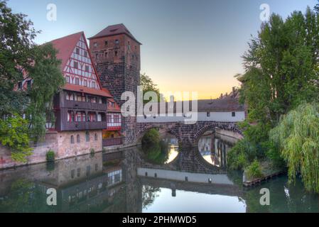 Blick auf den Sonnenaufgang auf das Weinstadel-Gebäude, den Wasserturm, die Henkerbrücke und den Henkerturm in Nürnberg. Stockfoto