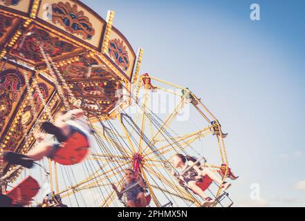 Kinder genießen eine klassische Fahrt auf dem „Flying Sessels“-Messegelände. Stockfoto