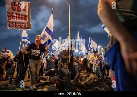 Tel Aviv, Israel. 25. März 2023. Reformfeindliche Demonstranten überqueren eine Barrikade, während sie während einer Reformdemonstration in Tel Aviv Schilder halten und israelische Flaggen schwenken. Mehr als 230.000 Menschen protestieren in Tel Aviv gegen Netanjahus rechtsextreme Regierung und ihre umstrittene Rechtsreform. (Credit Image: © Matan Golan/SOPA Images via ZUMA Press Wire) NUR ZUR REDAKTIONELLEN VERWENDUNG! Nicht für den kommerziellen GEBRAUCH! Stockfoto