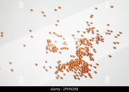 Viele kleine orangefarbene Kugeln, die auf einem weißen Hintergrund im hellen Licht verstreut sind und Schatten fallen lassen. Geometrische abstrakte futuristische Tapete mit vielen Stockfoto