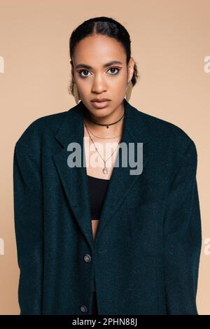 Junges afroamerikanisches Modell in dunkelblauem Wollblazer, isoliert auf beige, Stock Image Stockfoto