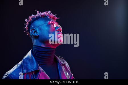 Mit Brille. Futuristische Neonbeleuchtung. Junger afroamerikanischer Mann im Studio Stockfoto