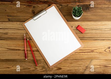 Leeres Tablet, Ansicht von oben, leeres weißes Blatt auf Holztisch, flaches Lay-Modell, Hintergrund mit PapierTablet-Struktur und Kopierbereich Stockfoto