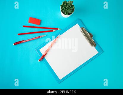 Leeres Tablet, Ansicht von oben, leeres weißes Blatt auf blauem Tisch, flaches Lay-Modell, Texturhintergrund des Papiertabletts mit Kopierbereich Stockfoto