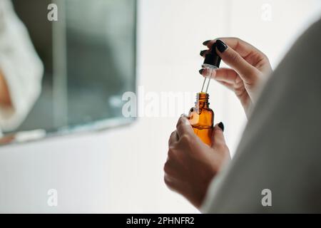 Hands of woman holding vial with face oil or retinol serum Stockfoto