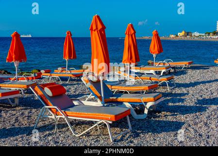 Sonnenliegen und Sonnenschirme am Strand in Rhodos Stadt in Griechenland. Stockfoto