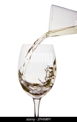 Gießen Sie Weißwein aus einer Karaffe in ein Weinglas Stockfoto