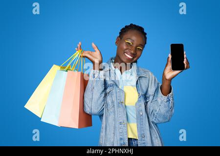 Glückliche junge schwarze Frau, die online einkauft, mit der mobilen App Stockfoto