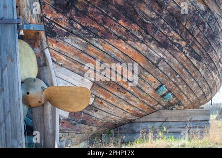 Ein altes verlassenes Schiffswrack aus Holz mit einem Kupferpropeller. Holzbohlen von einem alten Retro-Rumpf-Boot. Stockfoto