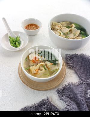 Zwei Schüsseln Wonton-Suppe mit Chilisauce und gehackten grünen Zwiebeln Stockfoto