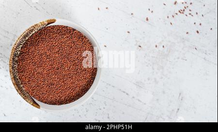 Kresse ( Lepidium sativum ) Samen in einer kleinen weißen Schüssel, Blick von oben, Platz für Text - leerer Steintisch - rechte Seite Stockfoto