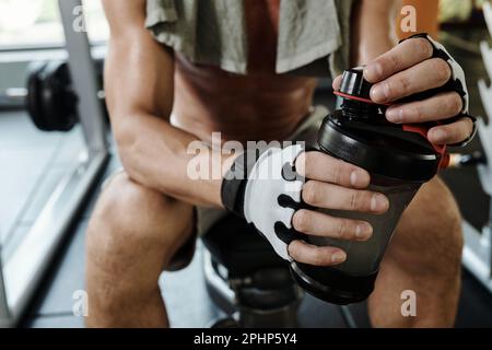 Die Hände eines Sportlers, der einen Shaker mit Proteincocktail hält Stockfoto