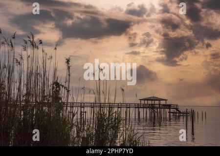 Am 27. März 2023 erstreckt sich ein Pier in Fairhope, Alabama, an einem bewölkten, aber ruhigen Nachmittag in Mobile Bay. Stockfoto