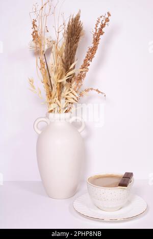 Eine wunderschöne Anordnung getrockneter Blumen in einer stilvollen weißen Vase. Beigefarbene Blumen auf weißem Hintergrund fotografiert, Bild-ID: 2PHP8NB Stockfoto