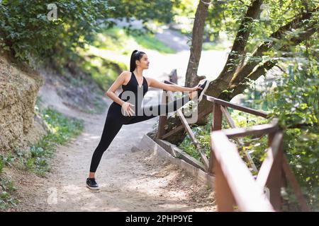 Zufriedene junge schwangere Frau, die einen gesunden Lebensstil führt und Yoga praktiziert, führt die Hanumanasana Übung, Längsfaden, Züge allein i Stockfoto