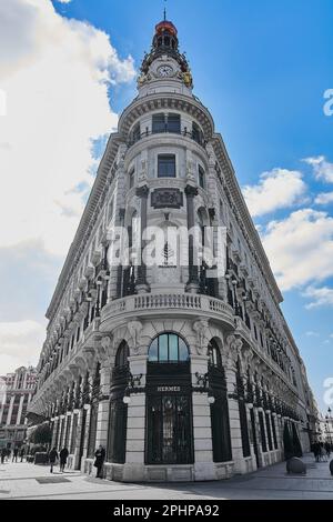 MADRID, SPANIEN - 29. März 2023: Four Seasons Hotel in Madrid mit der Büste des maestro Alonso zu seinen Füßen und einigen Personen, die zu Fuß gehen Stockfoto