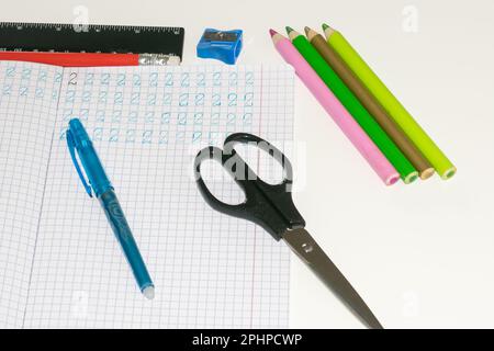 Ansicht eines Notizbuchs mit geschriebenen Zahlen, daneben ein Stift, ein Lineal, eine Schere eines Notizbuchs mit geschriebenen Zahlen, daneben ein Stift, ein Lineal Stockfoto