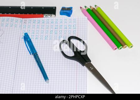 Ansicht eines Notizbuchs mit geschriebenen Zahlen, daneben ein Stift, ein Lineal, eine Schere eines Notizbuchs mit geschriebenen Zahlen, daneben ein Stift, ein Lineal Stockfoto