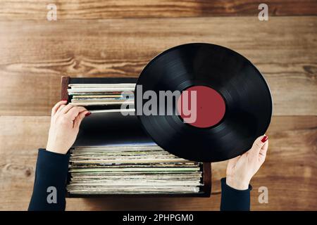 Vinyl-Schallplatten spielen. Musik von einem Vinyl-Plattenspieler hören. Retro- und Vintage-Musikstil. Frau mit analogem LP-Plattenalbum. Stapel alt Stockfoto