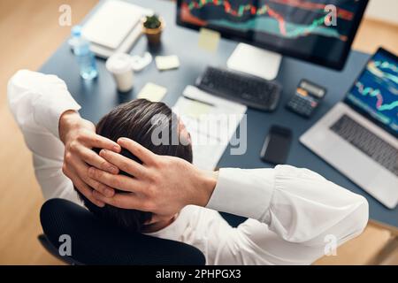 Besorgter Geschäftsmann, der sich Diagramme ansieht, die von den Neuigkeiten der Börse gestresst werden. Investor hat online Geld verloren. Man analysiert Verlust und Gewinn. Geschäftsmann investiert Stockfoto