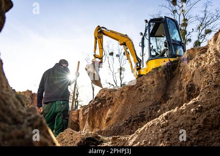 Aushub- und Erdarbeiten auf einer Baustelle mit einer Person und einem Hydraulikbagger Stockfoto