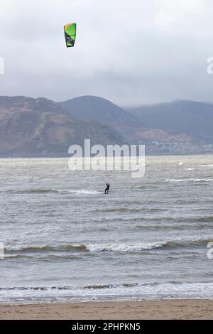 Ein einzelner Kitesurfer mit Brett, Gurtzeug und Folie, der den Nervenkitzel des Surfens in anspruchsvollen Meeren vor der Westküste von Llandudno, Nordwales, genießt Stockfoto