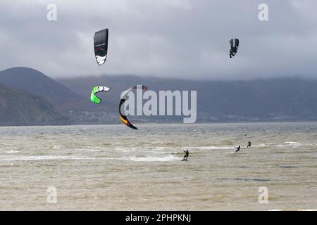 Kitesurfer genießen den Nervenkitzel des Surfens in wilden und windigen Gewässern vor der Westküste von Llandudno in der Flussmündung des Conwy Stockfoto