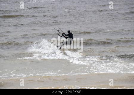 Kitesurfer genießen den Nervenkitzel des Surfens auf gehacktem und welligem Wasser am Westufer von Llandudno bei windigen Bedingungen Stockfoto