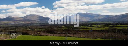 Ein Panoramablick auf Snowdon Yr Wyddfa, den höchsten Gipfel und die Carneddau Bergkette im Snowdonia-Nationalpark, Nordwales, von Anglesey aus gesehen. Stockfoto