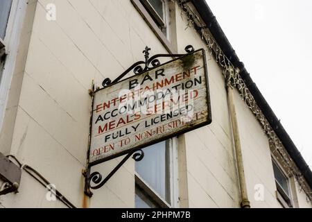 Schild vor einem heruntergekommenen Hotel mit der Aufschrift „Bar, Unterhaltung, Unterkunft, Mahlzeiten serviert, voll lizenziert, Offen für Gebietsfremde Stockfoto