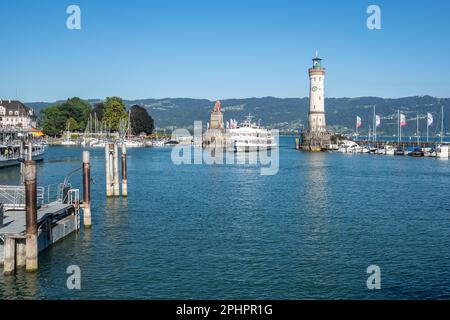 Eine Fähre im Hafen von Lindau, die zwischen dem Leuchtturm und der berühmten bayrischen Löwenskulptur Bayern vorbeifährt Stockfoto