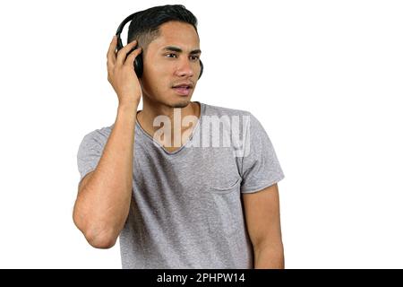 28-jähriger Brasilianer mit kabellosem Kopfhörer, Musik hören und zur Seite schauen. Stockfoto