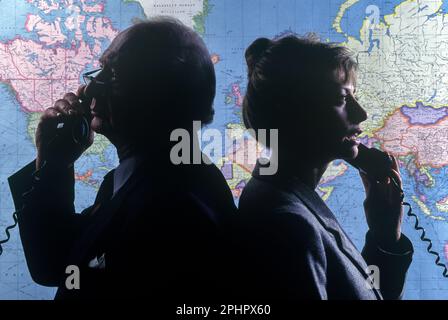 1990 GESCHICHTSTRÄCHTIGE BÜROANGESTELLTE, DIE AUF DER WELTKARTE MIT TELEFONEN STEHEN („RAND MCNALLY 1990“) Stockfoto