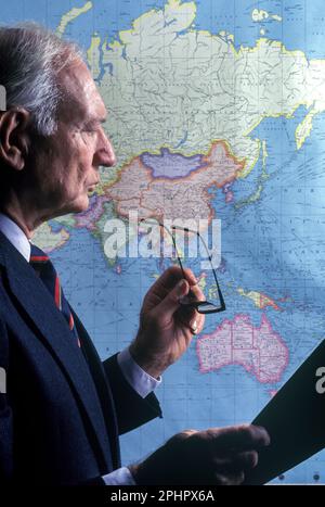 1990 GESCHICHTSTRÄCHTIGER MÄNNLICHER BÜROANGESTELLTER, DER ASIEN AUF DER WELTKARTE BETRACHTET („RAND MCNALLY 1990“) Stockfoto