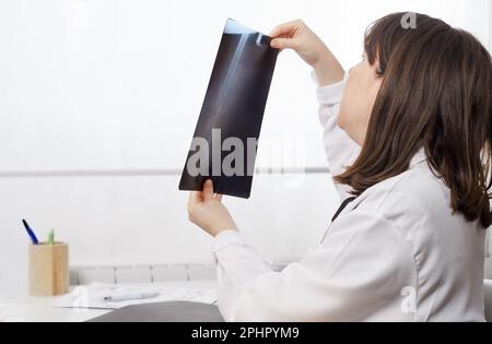 Eine junge Ärztin, die die Röntgenaufnahmen eines Patienten untersucht Stockfoto