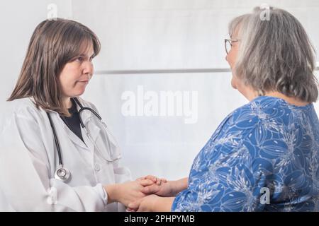 Eine junge Ärztin, die eine ältere Patientin konsultiert und beruhigt Stockfoto