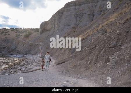 Mutter und Tochter in Sportbekleidung und mit Rucksäcken wandern durch den Wald und die Berge. Touristen kleben im Wacholdergesicht. Mutterliebe. Familienspaziergang in der Natur. Hochwertiges Foto Stockfoto